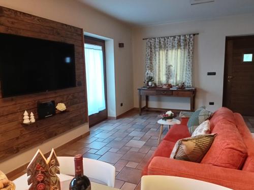 un soggiorno con divano rosso e TV a schermo piatto di La Sarrolein CIR 0009 ad Aosta