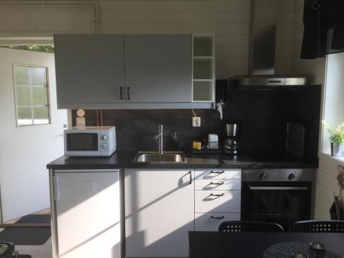 uma cozinha com armários brancos, um lavatório e um micro-ondas em Bränntorps Gård em Kolmården