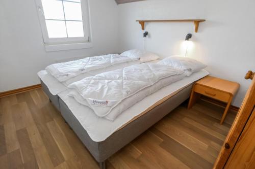 a bed with white sheets on it in a room at Charming thatched stone house by the sea - SJ241 in Harboør