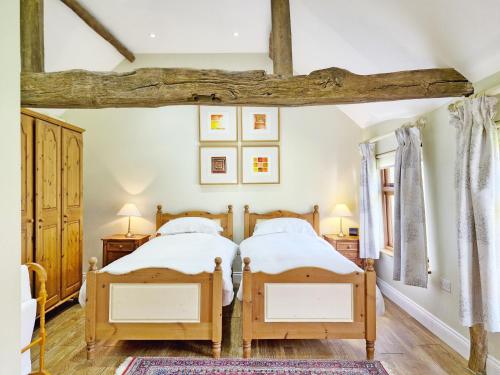 Walnut Cottage - Horsham في هورشام: سريرين توأم في غرفة نوم مع عوارض خشبية