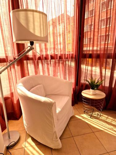 a living room with a white chair and a lamp at Sierco Apartamentos Ainsa in Aínsa
