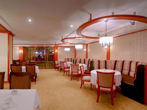 a restaurant with white tables and chairs and a chandelier at Buudai hotel in Darkhan