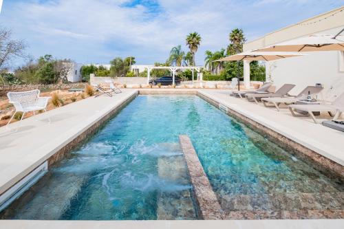 an infinity pool with chairs and an umbrella at Villa Zorro Luxury - Marina di Mancaversa in Marina di Mancaversa