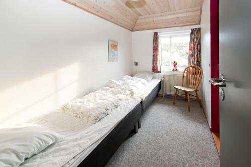 duże łóżko w pokoju z krzesłem w obiekcie Thatched house with pool by the sea - SJ690 w mieście Harboør
