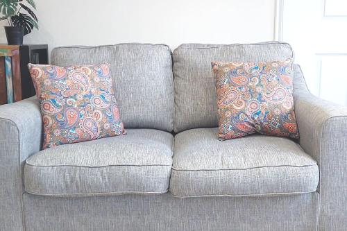 a gray couch with two pillows on it at Paisley Pattern Flat West End UWS UNI GLA Glasgow Airport in Elderslie