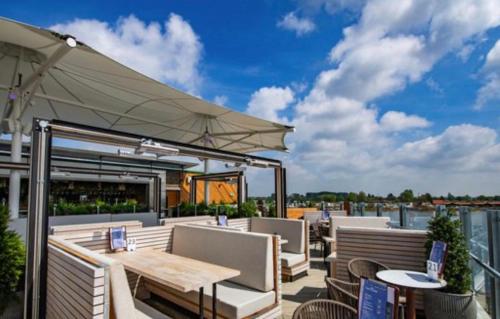 a patio with tables and chairs and an umbrella at Shells Breaks Tattershall Lakes Shearwater 27 in Tattershall