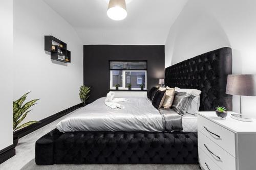 1 dormitorio con 1 cama grande y cabecero negro en Luxury by the Sea, Beautiful 3 bedroom House with Fast WiFi, King Bed, Lovely Garden! Blackpool's Finest Getaway Experience for up to 8 Guests! en Blackpool