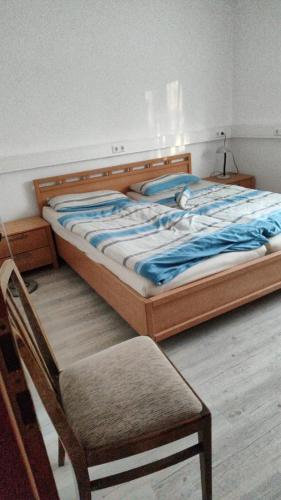ein Bett mit einem Holzrahmen und einem Stuhl in einem Zimmer in der Unterkunft Einliegerwohnung Gretels Idyll in Rot am See