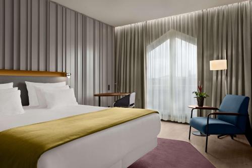 a hotel room with a bed and a blue chair at NH Collection Amsterdam Flower Market in Amsterdam