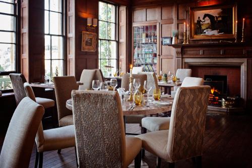 a dining room with a table and chairs and a fireplace at Burleigh Court Hotel in Stroud