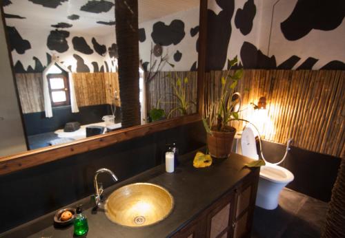 een badkamer met een wastafel, een toilet en een spiegel bij Olive Branch Farm in Raghunāthpur