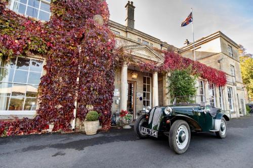 an old car parked in front of a building covered in flowers at Burleigh Court Hotel in Stroud