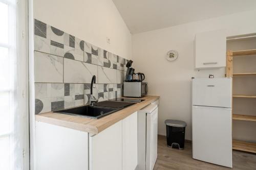a kitchen with a sink and a refrigerator at Au petit chez nous in Cozes