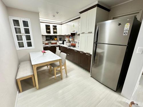 a kitchen with a table and a stainless steel refrigerator at Memory - Internationals Only in Daegu