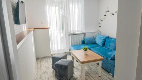 a living room with a blue couch and a table at Dom Wczasowy BiuLux in Mielno