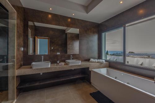 baño con 2 lavabos, bañera y ventana grande en Villa Lord Hammon en Gammarth