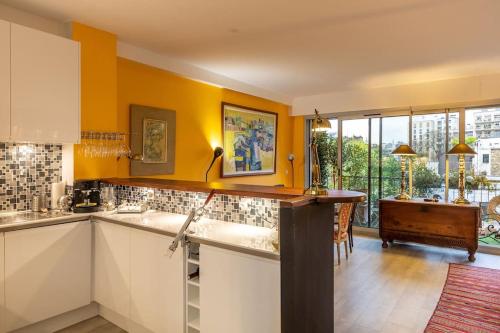 une cuisine avec des murs jaunes et un comptoir. dans l'établissement L'ASSOMPTION Appartement de charme avec balcon, à Paris