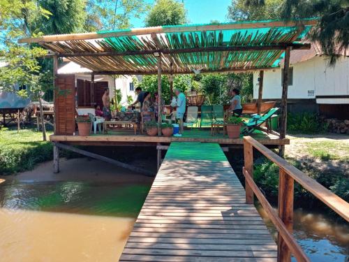 a wooden bridge with a pergola over a river at Lodge Gloria in Dique Luján