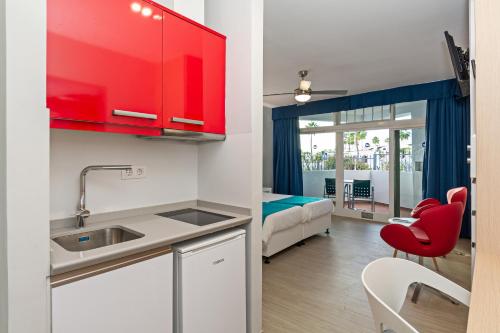 a kitchen with red cabinets and a bedroom with a bed at Apartamentos Panorama Adults Only in Puerto del Carmen
