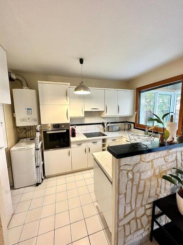 une cuisine avec des armoires blanches et un comptoir noir dans l'établissement Appartement calme avec jardin proche de Paris, à Évry-les-Châteaux
