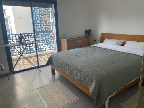 ein Schlafzimmer mit einem Bett und einem großen Fenster in der Unterkunft MARTIL COSTA MAR Appartement de Luxe in Martil