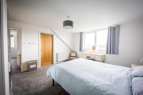 a white bedroom with a bed and a window at Harbour View Goodwick in Goodwick