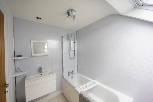a white bathroom with a shower and a sink at Harbour View Goodwick in Goodwick