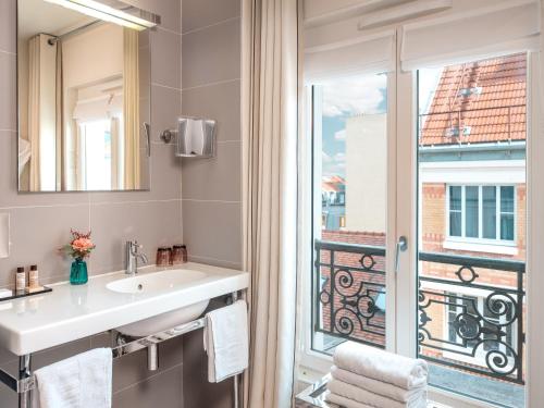 a bathroom with a sink and a window at Hotel Le Mareuil in Paris