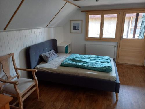 a small bedroom with a bed and a chair at Chalet Bärenhaus in Sigriswil