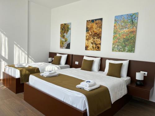 two beds in a room with paintings on the wall at Apart Hotel Perla Resort Lalez Durres in Durrës