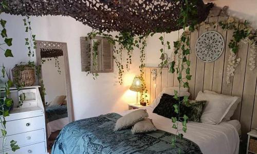 ラ・モットにあるSIANDAKI - logement romantique de charmeのベッドルーム1室(壁に植物が飾られたベッド1台付)