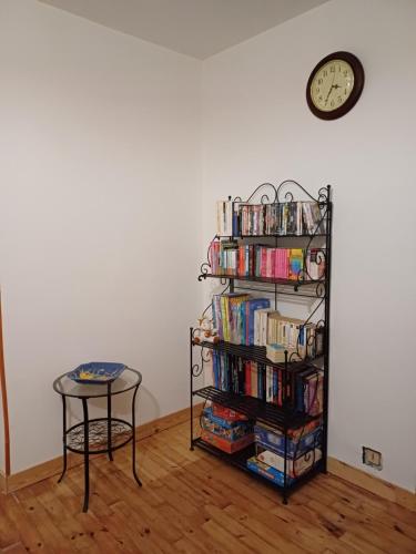 a book shelf filled with books next to a clock at E lu chantauziau in La Monnerie-le Montel