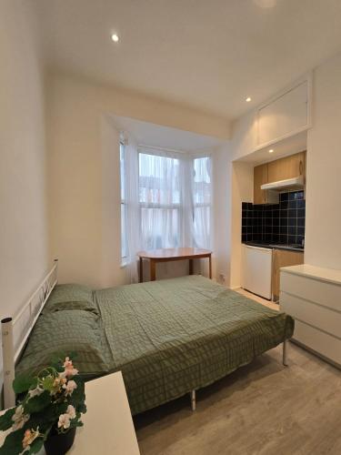 a bedroom with a bed and a desk and a kitchen at RELAKS LETTINGS in London
