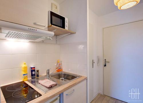 une cuisine avec un évier et un micro-ondes dans l'établissement Le Caducé / Proche Deux Lions, à Tours
