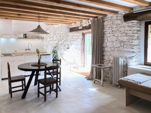 uma cozinha e sala de jantar com uma mesa e uma parede de pedra em Mañarinegi Apartamentos Rurales em Aia