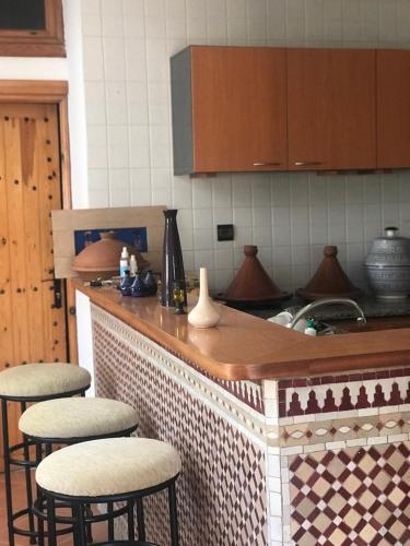 une cuisine avec comptoir et tabourets de bar dans l'établissement Appartement atypique et lumineux, à Agadir