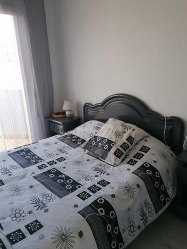 een bed met een zwart-witte deken en kussens bij Le sagittaire in Port-la-Nouvelle