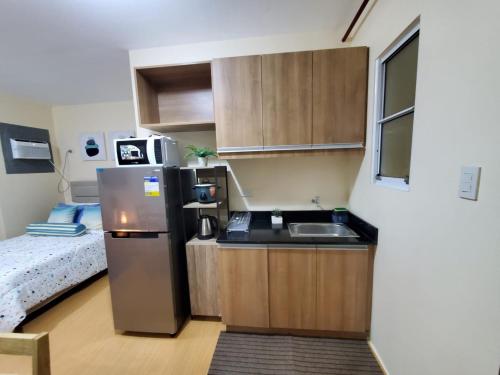 a small kitchen with a sink and a refrigerator at COZY STUDIO DELUXE with Pool, Free Parking & Basket Ball Court , Pet Friendly Condo in Manila