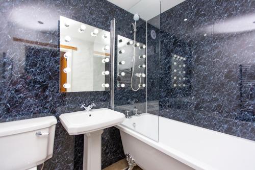 a bathroom with a sink and a tub and a mirror at The Old Cowshed Haverfordwest in Haverfordwest