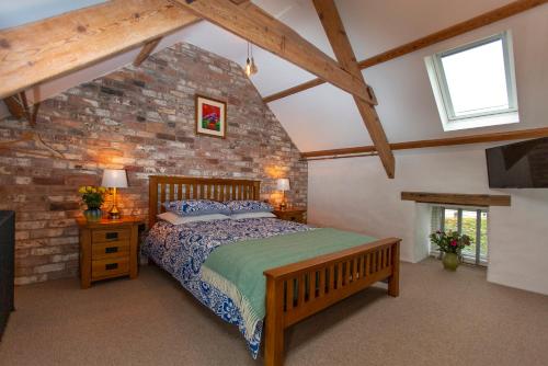 ein Schlafzimmer mit einem Bett und einer Ziegelwand in der Unterkunft The Old Cowshed Haverfordwest in Haverfordwest