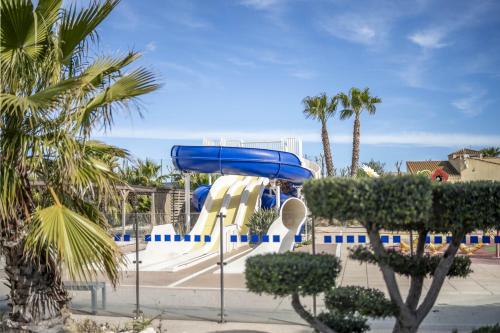 - un toboggan aquatique dans une piscine bordée de palmiers dans l'établissement Chez Christian et Sophie, à Valras-Plage