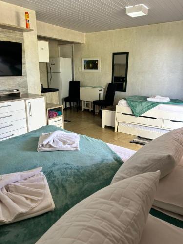 a bedroom with two beds and a living room at Flats Baia dos Porcos in Fernando de Noronha