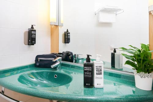 W łazience znajduje się zielona umywalka z lustrem. w obiekcie Ibis Como w mieście Grandate