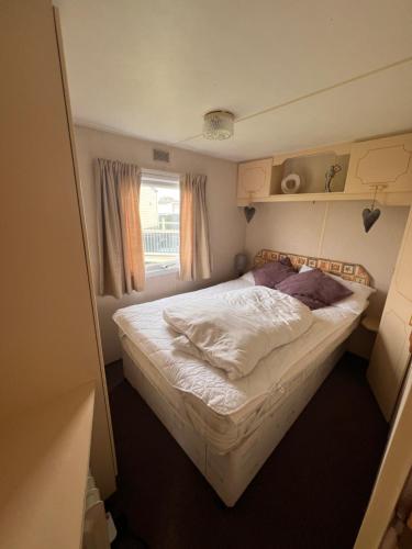 a small bed in a small room with a window at AMS Caravan Holidays in Ingoldmells