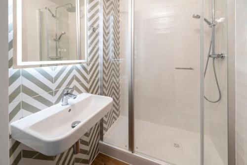 La salle de bains est pourvue d'un lavabo et d'une douche. dans l'établissement Le Carline, Sure Hotel Collection by Best Western, à Caen