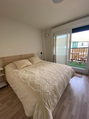 une chambre avec un lit et une grande fenêtre dans l'établissement Appartement baie de Chingoudy, à Hendaye