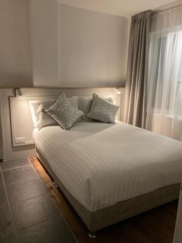sypialnia z dużym białym łóżkiem i oknem w obiekcie Cille Apartments, Ballyferriter village w mieście Ballyferriter