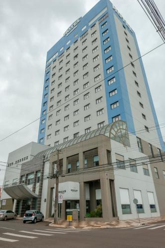 un gran edificio con un coche aparcado delante de él en Hotel Executive Arapongas, en Arapongas