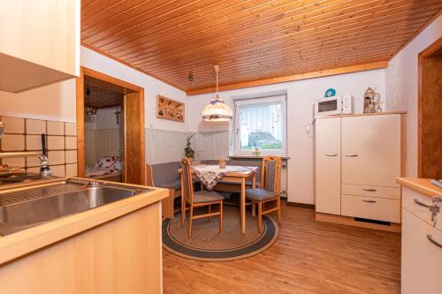 a kitchen with a table and a white refrigerator at Haus am Wald in Bad Koetzting