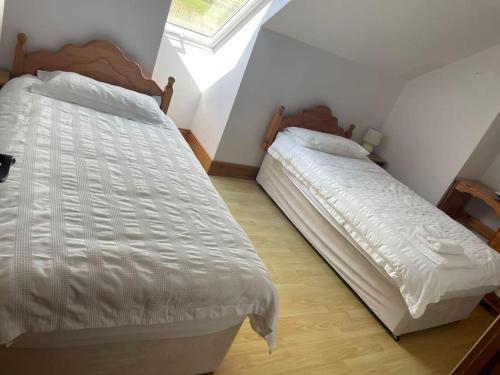 a bedroom with two beds and a window at 1 Bray Head View in Portmagee